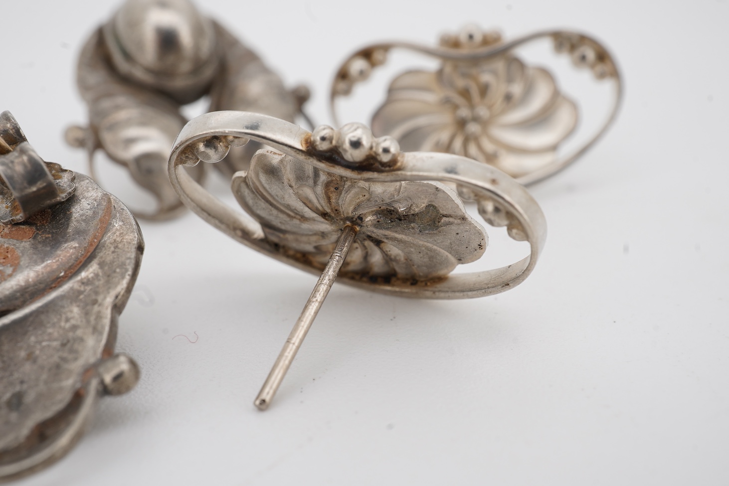 Two pairs of Georg Jensen sterling ear studs, one pair of leaf and berry design, 18mm and flower head form, design no. 52, lacking butterflies.